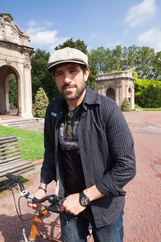 Middle-aged hipster traveler walking through the city with an urban bike