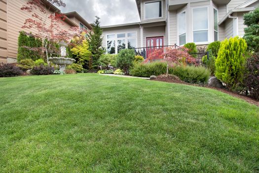 Green Grass Lawn in house front yard manicured garden with water fountain trees plant shrubs rocks in landscaping