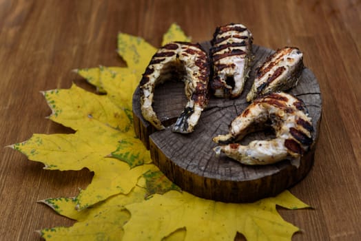 fish steaks fried on the grill lying on tree trunk against the yellow maple leaves