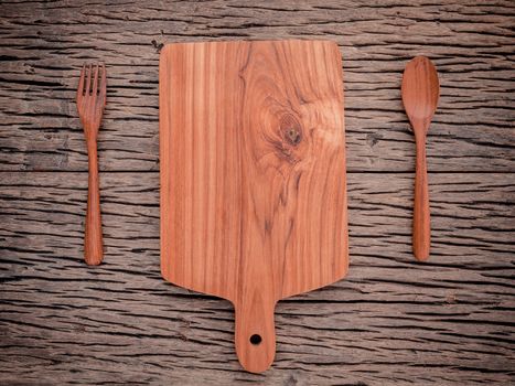 Empty vintage Teak wood cutting board ,fork and spoon on grunge wood food background concept.