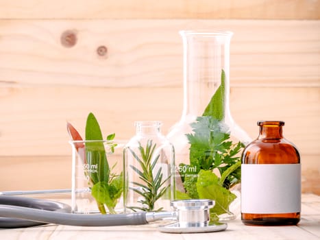 Alternative health care fresh herbal in laboratory glassware  with  stethoscope on wooden background.