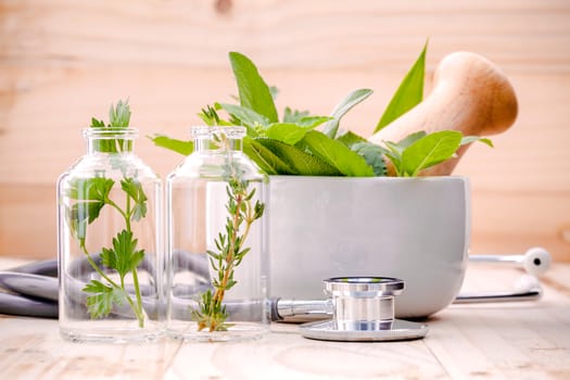 Alternative health care fresh herbal in laboratory glassware  with  stethoscope on wooden background.