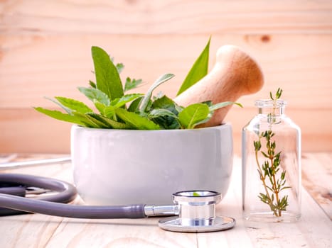 Alternative health care fresh herbal in laboratory glassware  with  stethoscope on wooden background.