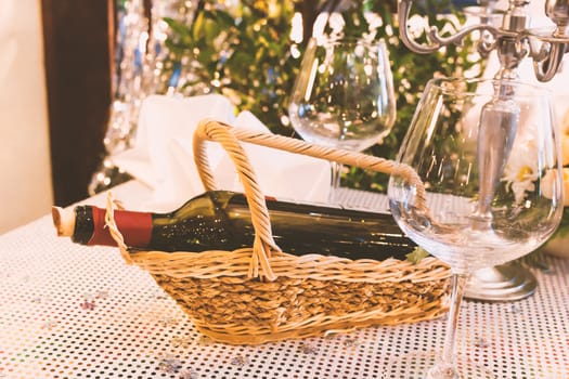 Bottle of wine on wood basket and Glasses on table.