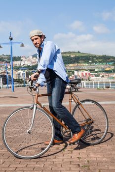 Happy middle-aged man with Irish beret bike riding enjoying a walk through the city