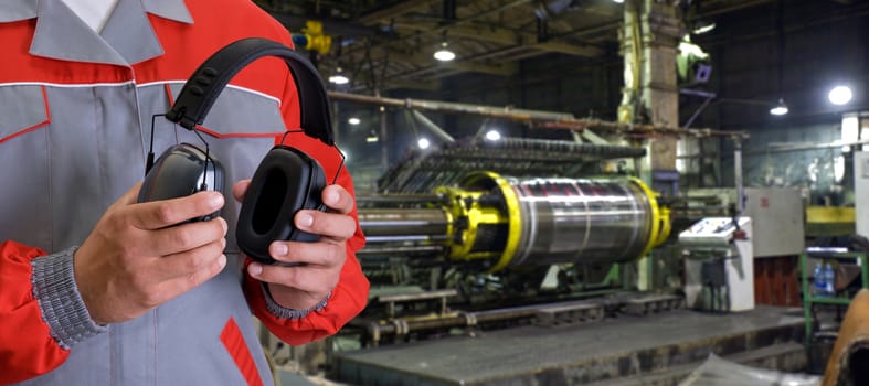 Worker with protective headphone at man hands at industrial factory