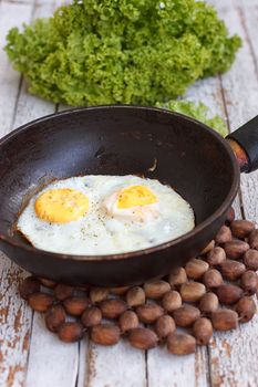 Scrambled eggs in an iron pan on the rustic wooden table