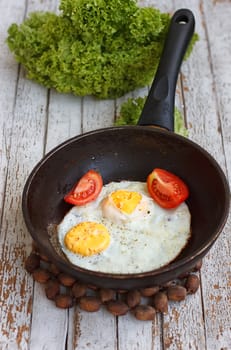 Scrambled eggs in an iron pan on the rustic wooden table