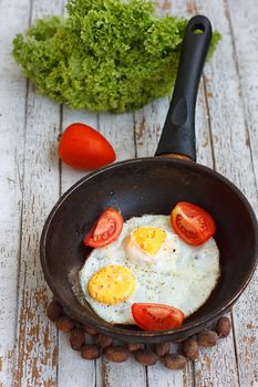 Scrambled eggs in an iron pan on the rustic wooden table