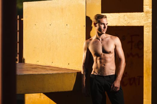 Young fit shirtless man exercising on outdoor sports ground. Concept: healthy lifestyle