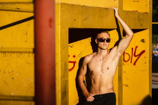 Young fit shirtless man exercising on outdoor sports ground. Concept: healthy lifestyle