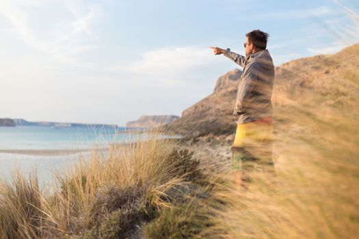 Sporty active man pointing hand on horizon, enjoying beauty of nature, freedom and life at beautiful landscape. Active lifestyle outdoors.