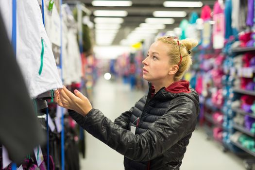 Beautiful caucasian woman shopping sportswear in sports store.