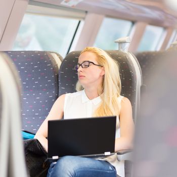 Businesswoman naping sitted while traveling by train and working on laptop. Tiresome business travel.