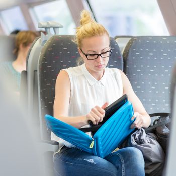 Businesswoman sitting and traveling by train working on laptop. Business travel concept.