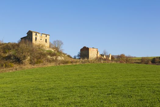 Panoramic view of a field for the agriculture with an old farm in the background