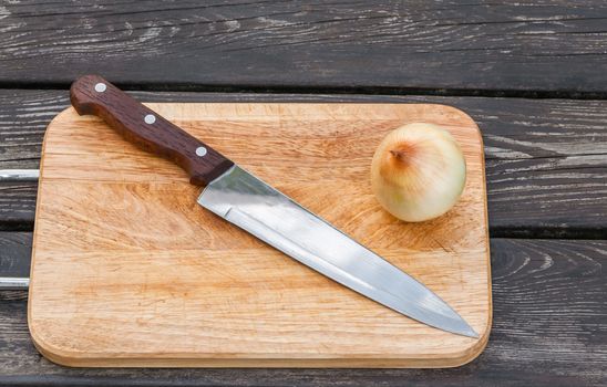 Steel knife,onion and a cutting chopping board