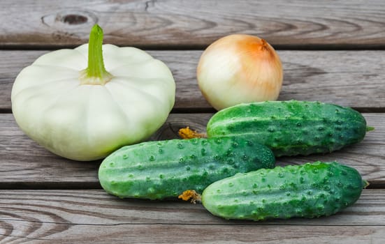 Squash, onions and cucumbers on a wooden table