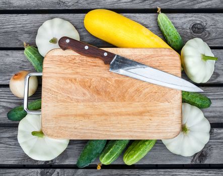 Cutting board, knife, fresh vegetables on wooden table.  Top view with copy space.