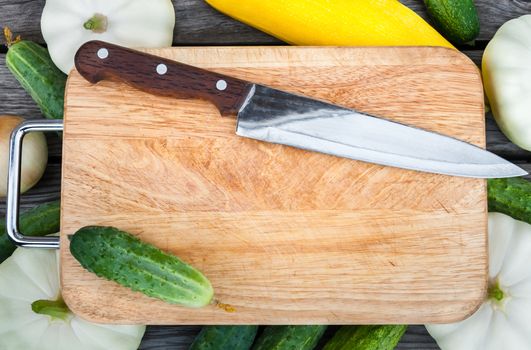 Cutting board, knife, fresh vegetables on wooden table.  Top view with copy space.