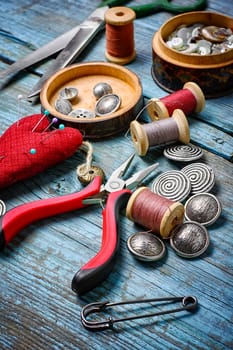 Scissors ,iron, stylish old-fashioned buttons and thread on wooden background
