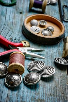 Scissors ,iron, stylish old-fashioned buttons and thread on wooden background