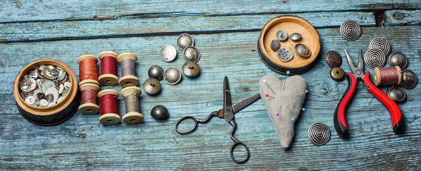 Scissors ,iron, stylish old-fashioned buttons and thread on wooden background