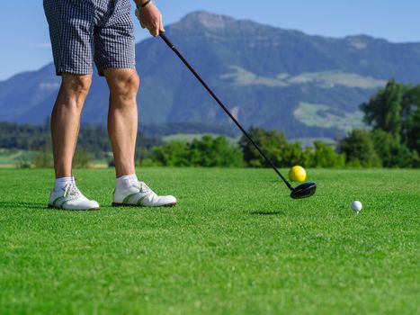 Photo of a male golfer teeing off on a golf course on a beautiful day.