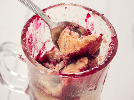 Mug Cake in glass mug with berries on white wooden background, close up