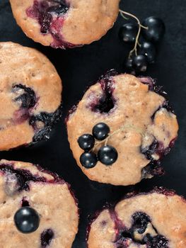 Muffins with black currant on dark background close up. Top view or flat lay