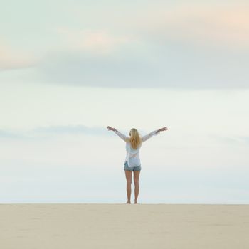 Relaxed woman enjoying freedom feeling happy at beach at dusk. Serene relaxing woman in pure happiness and elated enjoyment with arms raised outstretched up. 