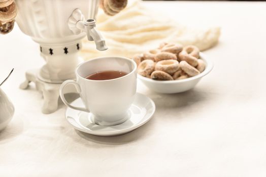 a samovar with bagels and hot tea on the white tablecloth