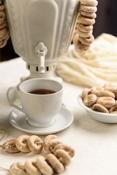 a samovar with bagels and hot tea on the white tablecloth