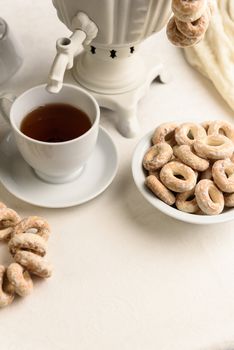 a samovar with bagels and hot tea on the white tablecloth