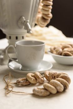 a samovar with bagels and hot tea on the white tablecloth