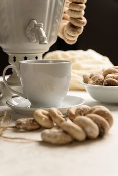 a samovar with bagels and hot tea on the white tablecloth