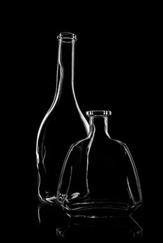 transparent bottle of brandy on a black background with reflection