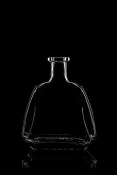 transparent bottle of brandy on a black background with reflection