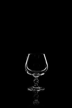 transparent glass for brandy or cognac on black background with reflection