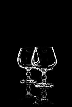 transparent glass for brandy or cognac on black background with reflection