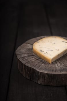 yellow cheese with seeds on a wooden end of a tree