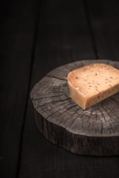 yellow smoked spicy cheese on a wooden end of a tree