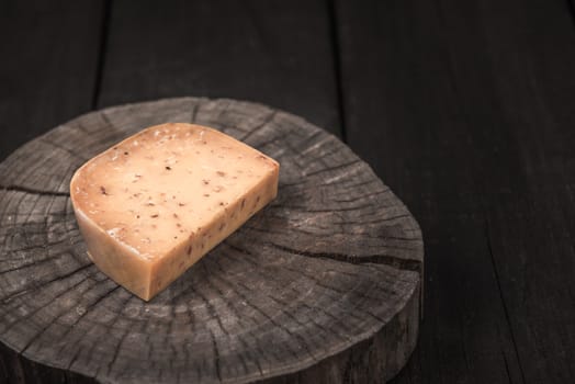 yellow smoked spicy cheese on a wooden end of a tree