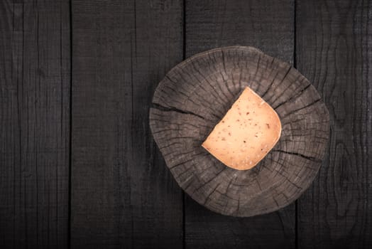 yellow smoked spicy cheese on a wooden end of a tree