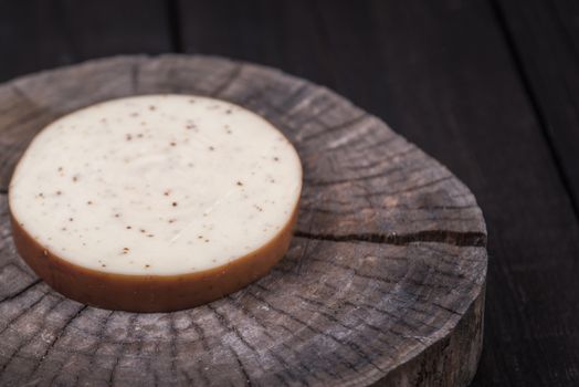 white milk cheese with seeds on a wooden end of a tree