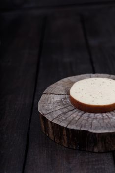 white milk cheese with seeds on a wooden end of a tree