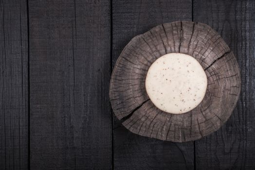 white milk cheese with seeds on a wooden end of a tree