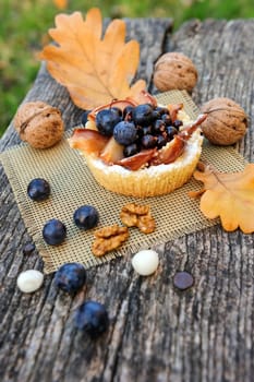Romantic autumn still life with basket cake, walnuts, blackthorn berries and leaves, in cold colors