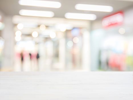 White wooden board empty table in front of blurred background. Perspective white wood over blur in shopping mall - can be used for display or montage your products. Mock up for display of product.