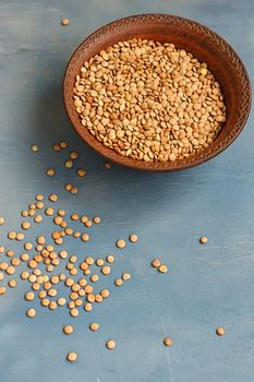 Green lentil in wooden bowl, on blue background